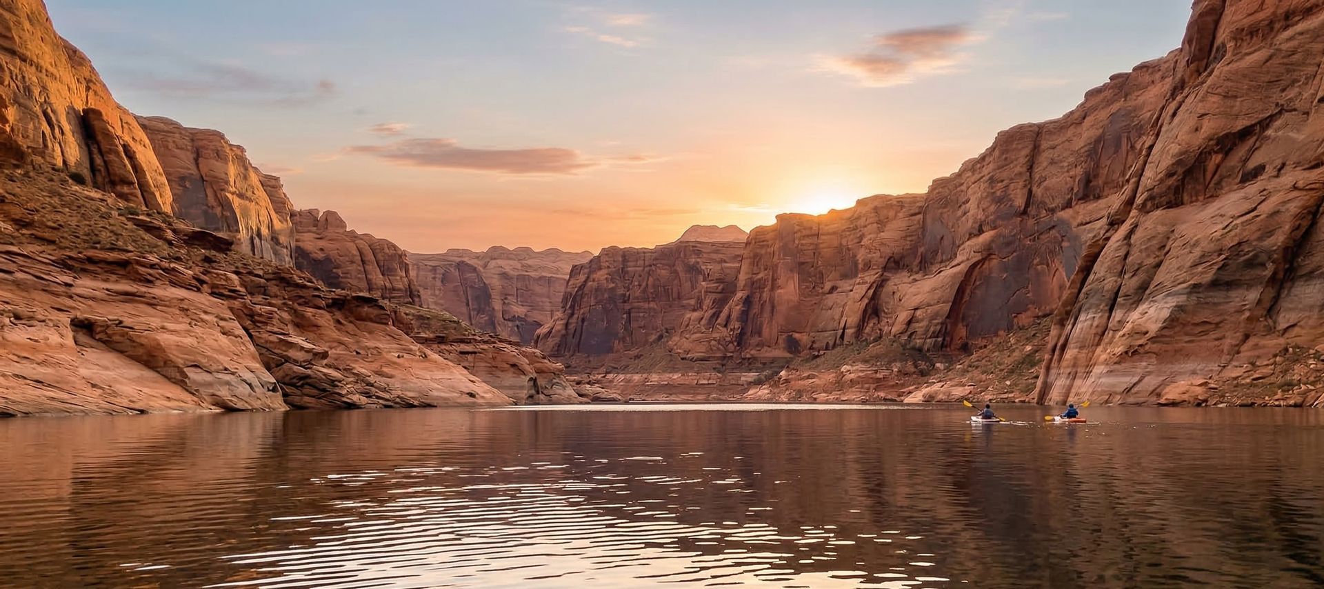 Kayakers paddling through a dramatic desert canyon at sunset